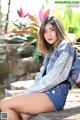 A woman sitting on top of a wooden bench.