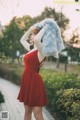 A woman in a red dress holding a blue fur stole.