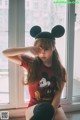 A young woman wearing a mickey mouse hat sitting on a window sill.