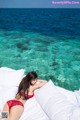 A woman in a red bikini laying on a bed.