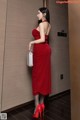 A woman in a red dress standing in an elevator.