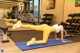 A woman doing a plank on a blue mat in a gym.