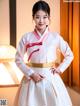 A woman in a white and pink hanbok posing for a picture.