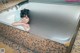 A woman laying in a bathtub with her legs in the water.