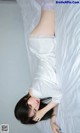 A woman laying on top of a bed in a white dress.