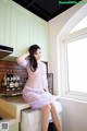 A woman sitting on top of a washing machine in a kitchen.