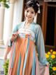 A woman in a blue and orange hanbok is posing for a picture.