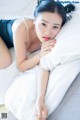 A woman laying on top of a bed next to a pillow.