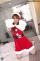 A woman in a santa claus outfit posing on a bed.