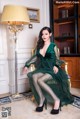 A woman in a green dress sitting on a chair.