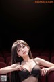 A woman in a black bikini sitting in a theater.