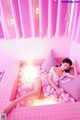 A woman laying in a pink bathtub filled with pink balls.