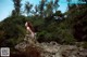 A woman sitting on top of a large rock.