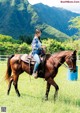 A woman riding on the back of a brown horse.