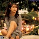 A woman sitting on the ground in front of a city street.