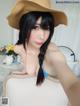 A woman in a straw hat is taking a selfie.