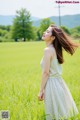 A woman standing in a field of green grass.