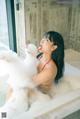 A woman in a bathtub with foam on her face.