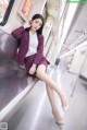 A woman in a purple suit sitting on a train.