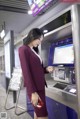 A woman in a red suit standing in front of an atm machine.