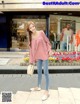 a woman standing in front of a store wearing a pink top