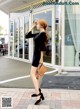 A woman in a black dress is walking down the street.