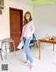 A woman in a pink sweater and jeans standing in a room.