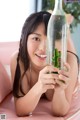 A young woman holding a bottle with a cactus in it.