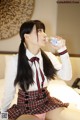 A woman in a school uniform drinking water from a bottle.