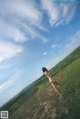 A naked woman standing on top of a lush green field.