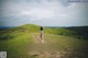 A woman standing on a dirt road in the middle of a field.