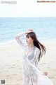 A woman standing on a beach next to the ocean.