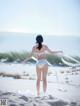 A woman in a white bikini standing on a beach.