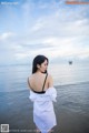 A woman in a white dress standing in the water.