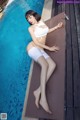 A woman in a white bikini laying on the edge of a pool.