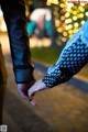 A man and a woman holding hands in front of a tree.