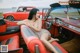 A woman sitting in the back seat of a red car.