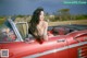 A woman sitting in the back of a red convertible car.