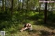 A naked woman laying on the ground in the woods.