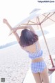 A woman in a blue and white checkered bikini standing on a beach.