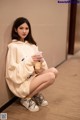 A woman sitting on the floor holding a cup of coffee.