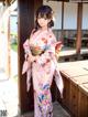 A woman in a pink kimono standing in front of a building.