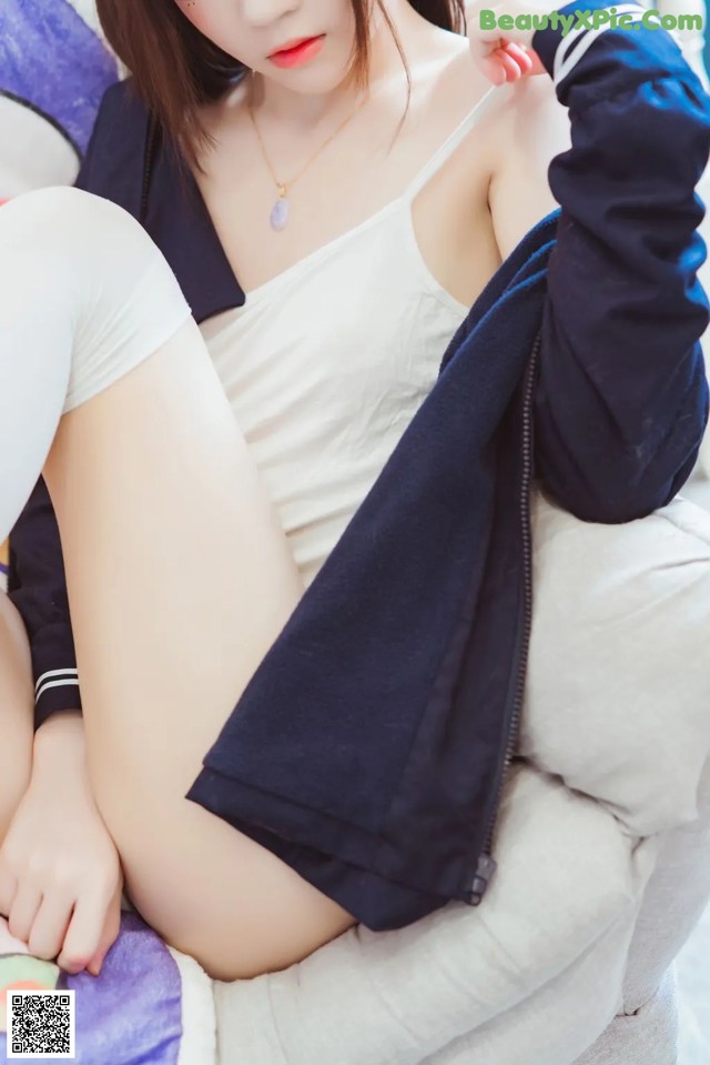 A woman sitting on top of a couch next to a pillow.