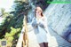 A woman in a white dress and fur coat standing on a wooden walkway.